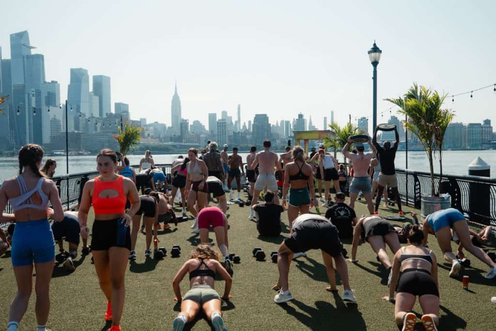 VTLZR members doing a group workout on the Jersey City waterfront with the Manhattan skyline behind them